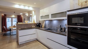 Een moderne keuken met witte kasten, een Bosch oven, en een eethoek met een tafel en stoelen.