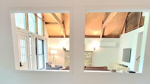 A room with wooden beams on the ceiling, a white wall with two windows, and four red stools. - Steps2Lake, BonusLoft, 2 full Baths, 7Beds, Pool Table, 2 Kayaks, 2 Arcade Games (Pocono Lake)