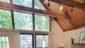 A spacious living room with a high ceiling, large windows, a fireplace, and a cozy seating area. - Steps2Lake, BonusLoft, 2 full Baths, 7Beds, Pool Table, 2 Kayaks, 2 Arcade Games (Pocono Lake)
