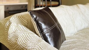 A close-up of a bed with a patterned pillow and a dark leather pillow.
