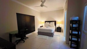 A hotel room with a bed, desk, chair, bedside tables, and a ceiling fan. - Waterfront Sanctuary Grande 4Bed 4Bath Pool Patio (Grand Harbour)