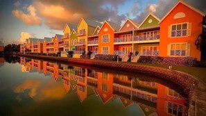 A row of brightly colored buildings with balconies, reflecting in a calm body of water. - Waterfront Sanctuary Grande 4Bed 4Bath Pool Patio (Grand Harbour)