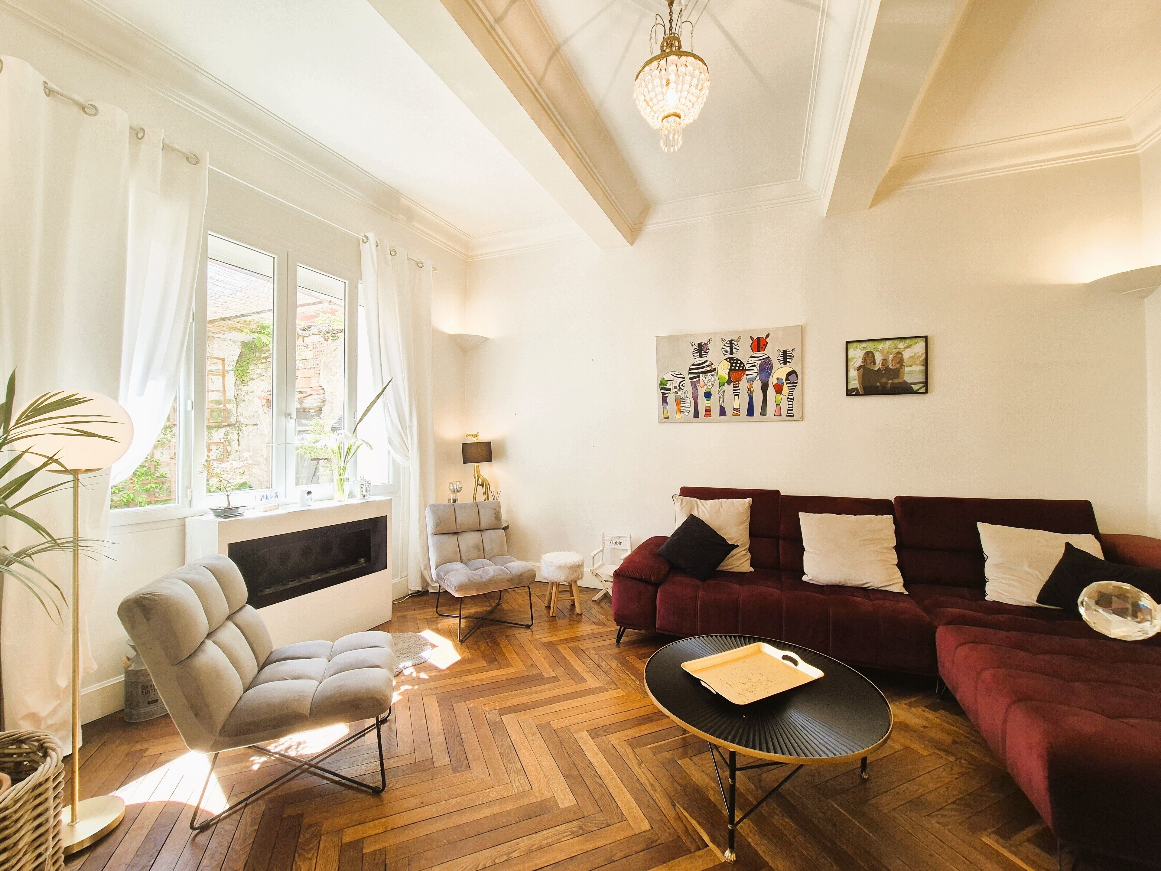 A living room with a fireplace, a sofa set, a coffee table, and a chandelier.