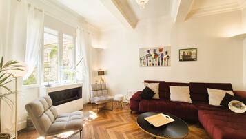A living room with a fireplace, a sofa set, a coffee table, and a chandelier.