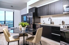 Una cocina moderna con un refrigerador negro, electrodomésticos de acero inoxidable y un amplio ventanal con vistas a la ciudad.