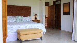 Ein Schlafzimmer mit einem Bett, einem Nachttisch, einer Bank und einem Holz-Kopfteil.