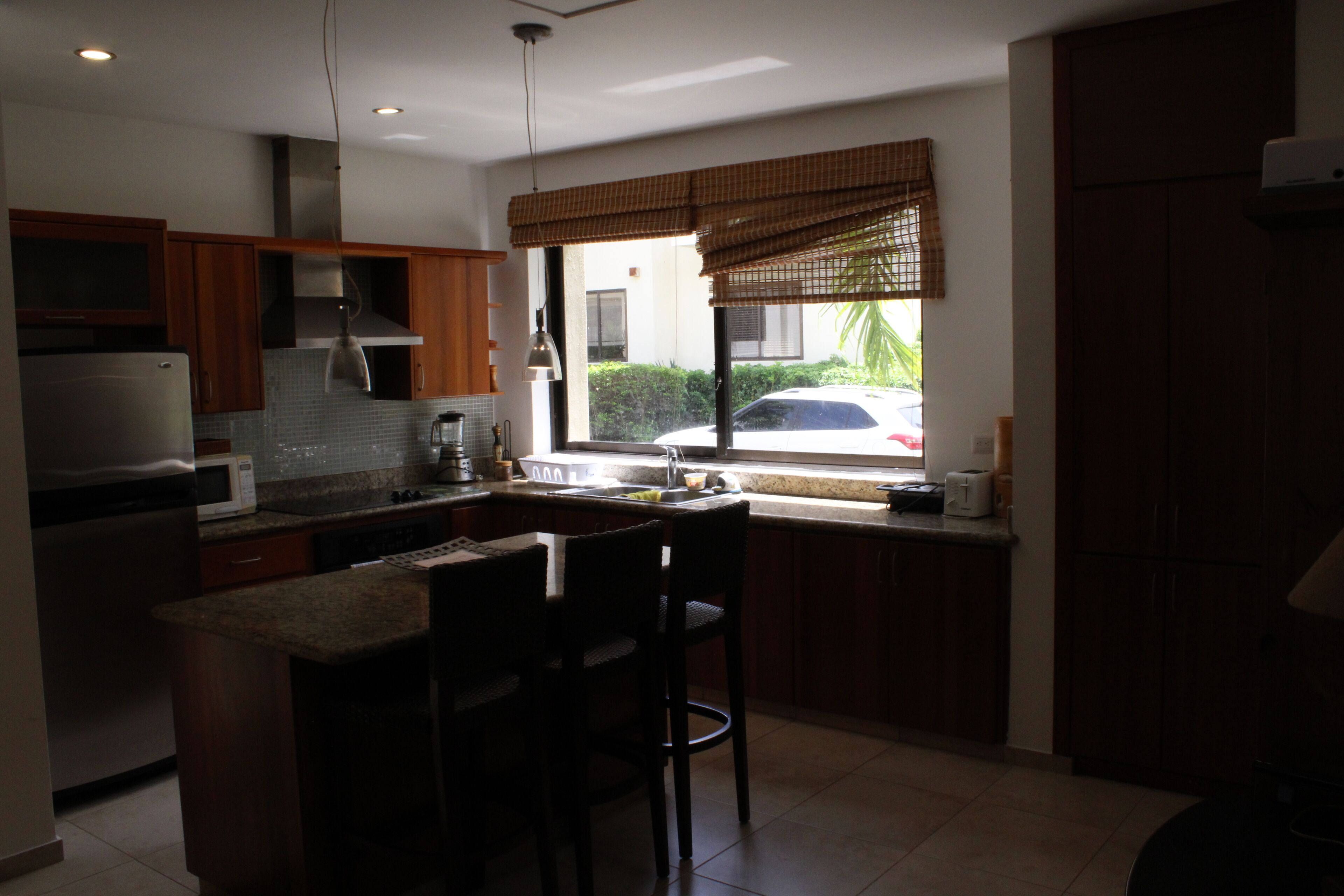 Una cocina moderna con armarios de madera, un microondas integrado y una ventana con vista a la calle.
