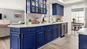 Eine moderne Küche mit blauen Schränken, einer weißen Arbeitsplatte und einem eingebauten Geschirrspüler.