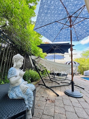 A statue of a seated figure, outdoor furniture, and patterned umbrellas.
