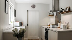 Une cuisine moderne avec des meubles blancs, un four encastré et un grille-pain. Un vase rempli de fleurs est posé sur la table à manger.
