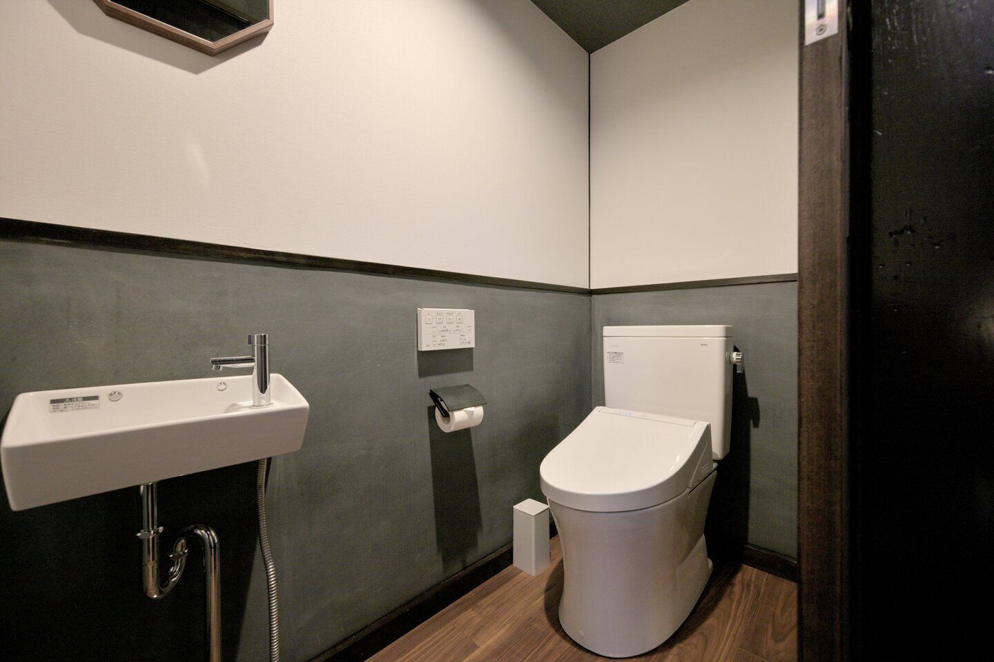 A compact bathroom with a white sink, toilet, and a small trash bin.