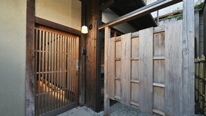 A traditional wooden gate with a metal lock, leading to a gravel pathway. - Takeya Tenmangu (Kyoto)