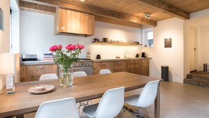 Una cocina moderna con armarios de madera, una mesa de comedor con sillas y un florero con flores.