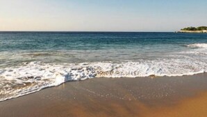A beach with clear blue water and a sandy shore.