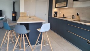 A modern kitchen with a central island, bar stools, a built-in stove, and a coffee maker.