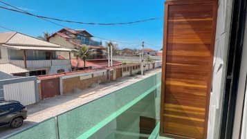 Zona residencial con casas, un coche y un balcón con puerta de madera.