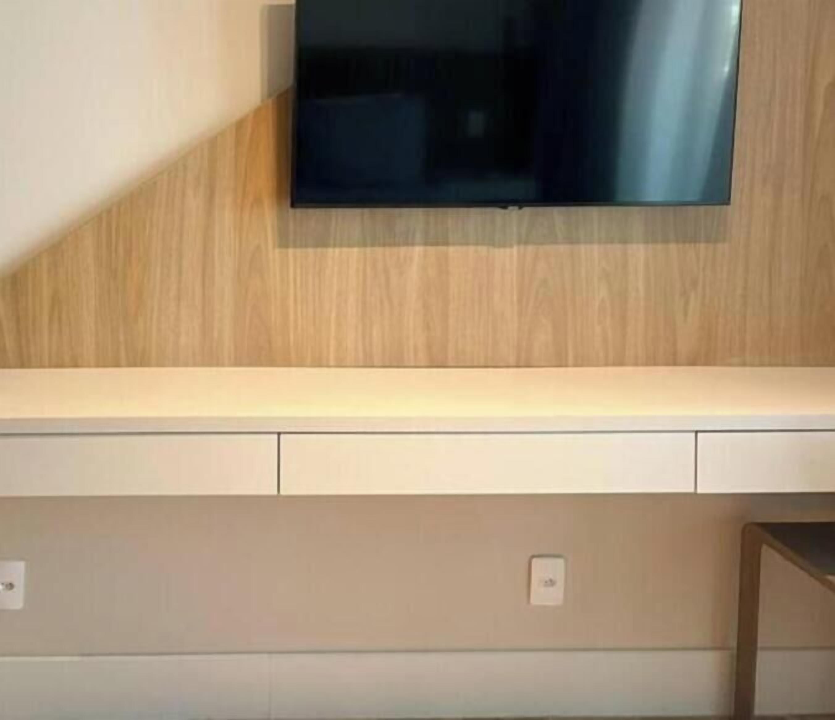A flat-screen TV mounted on a wall with a wooden panel design.