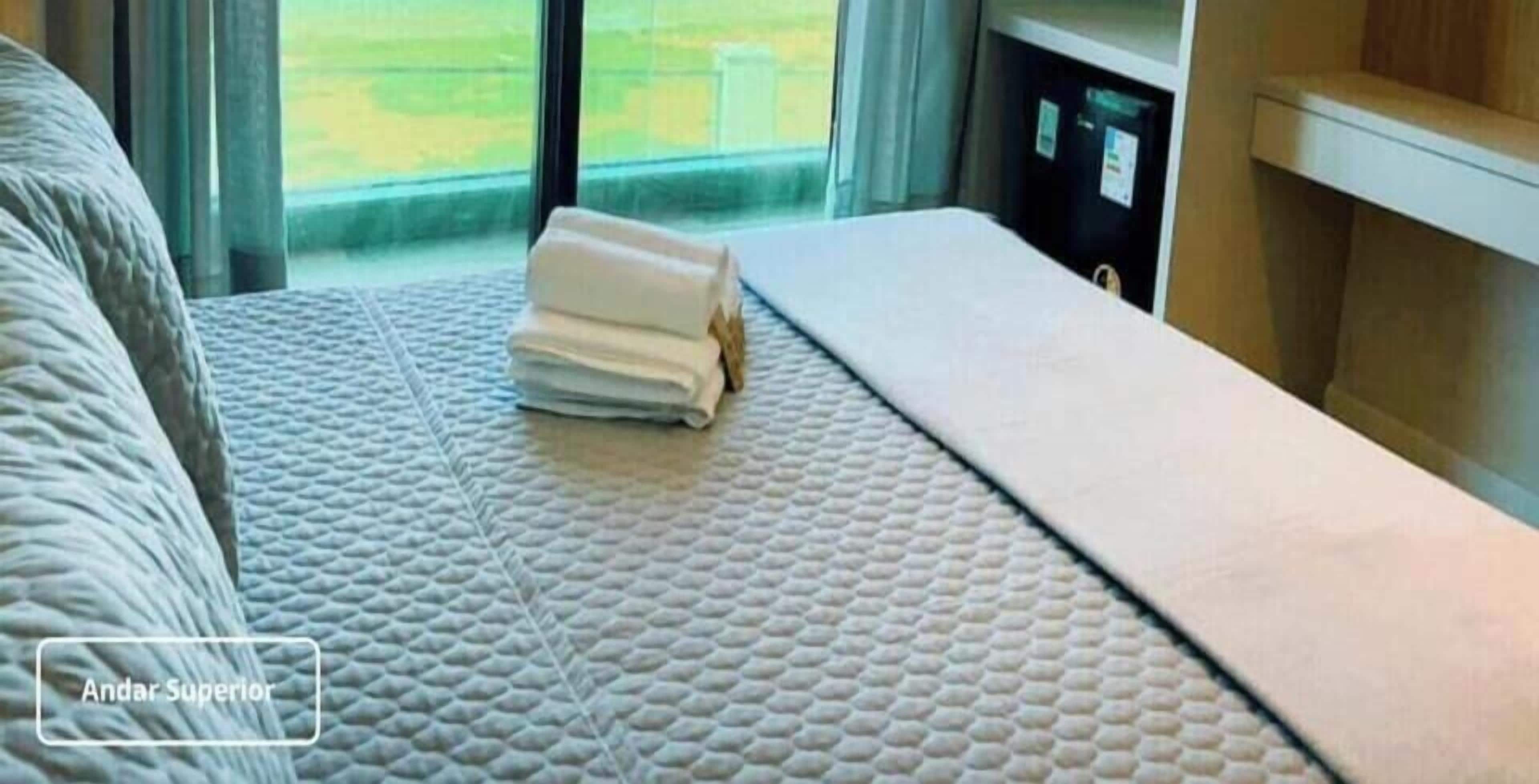 A hotel room with a bed, a window, and a view of the outdoors.