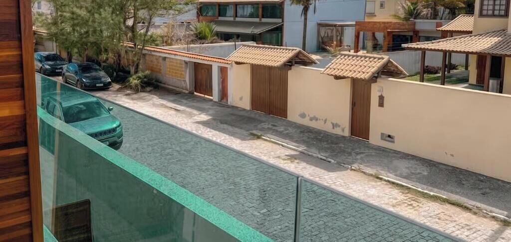 Una calle residencial con arboles, un camino pavimentado, autos estacionados y casas con techos de tejas.