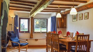A dining area with wooden furniture, a table set for four, and a view through the window.