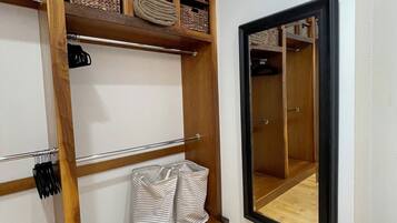 Ein begehbarer Kleiderschrank mit Holzböden, Körben und Kleiderstangen.