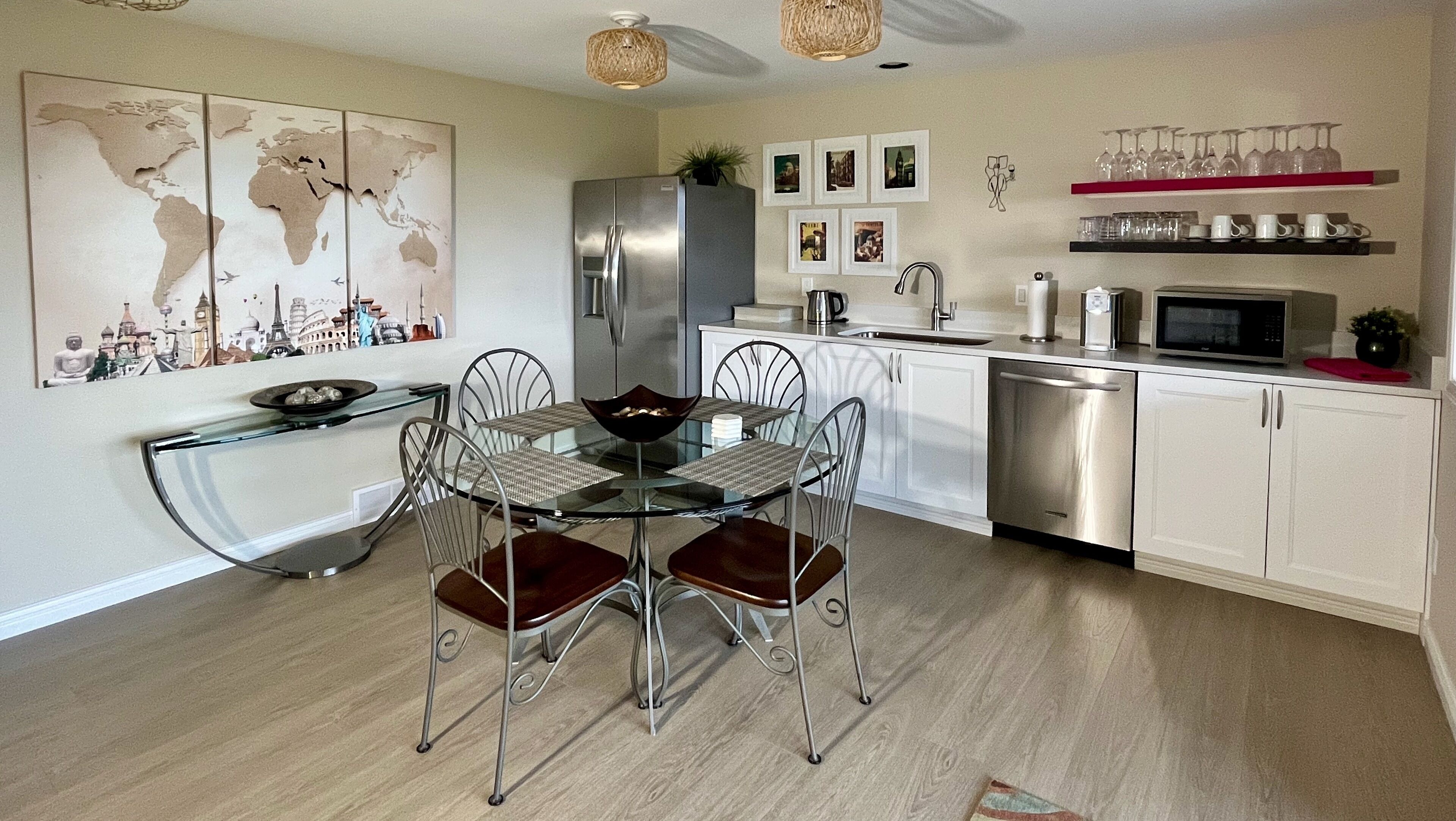 A modern kitchen with white cabinets, stainless steel appliances, and a glass dining table with metal chairs.