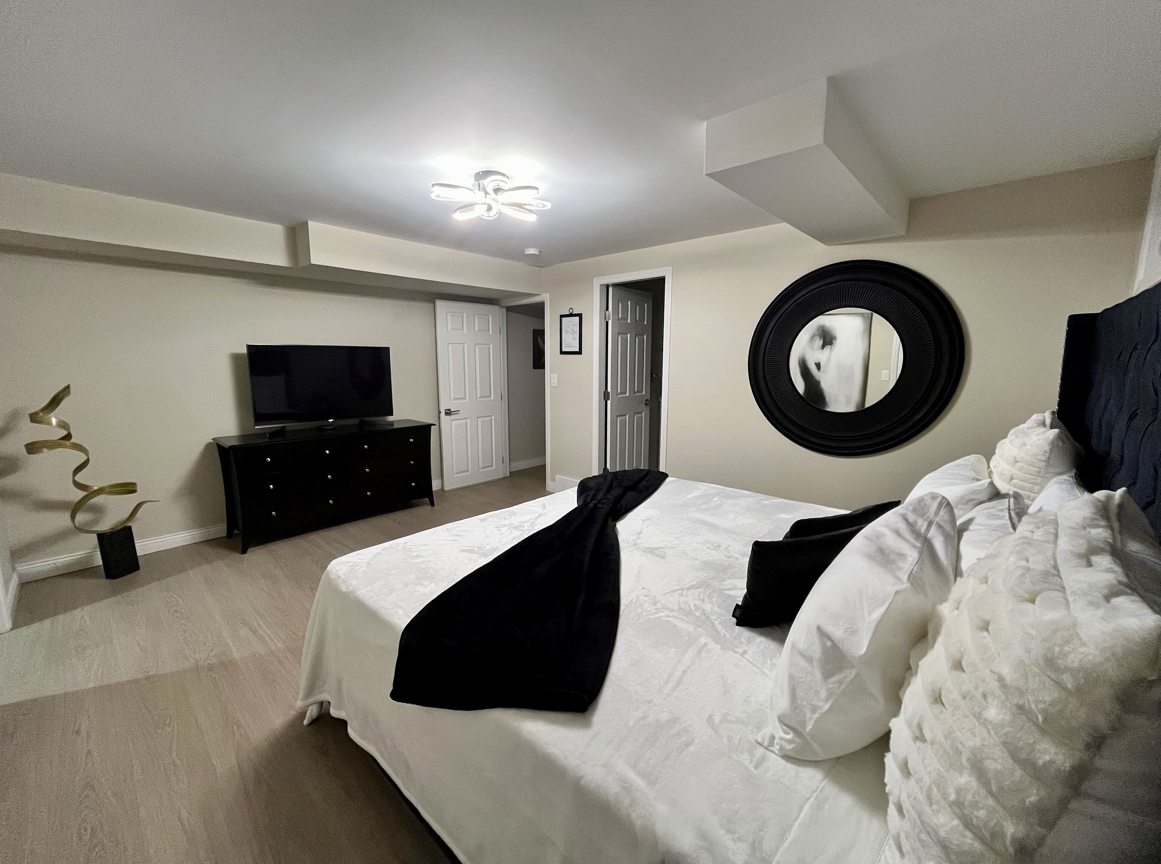 Un dormitorio con cama, cómoda, televisor, espejo y ventilador de techo.
