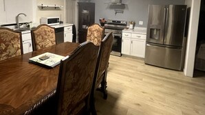 Una cocina moderna con una mesa de comedor, sillas y electrodomésticos de acero inoxidable.