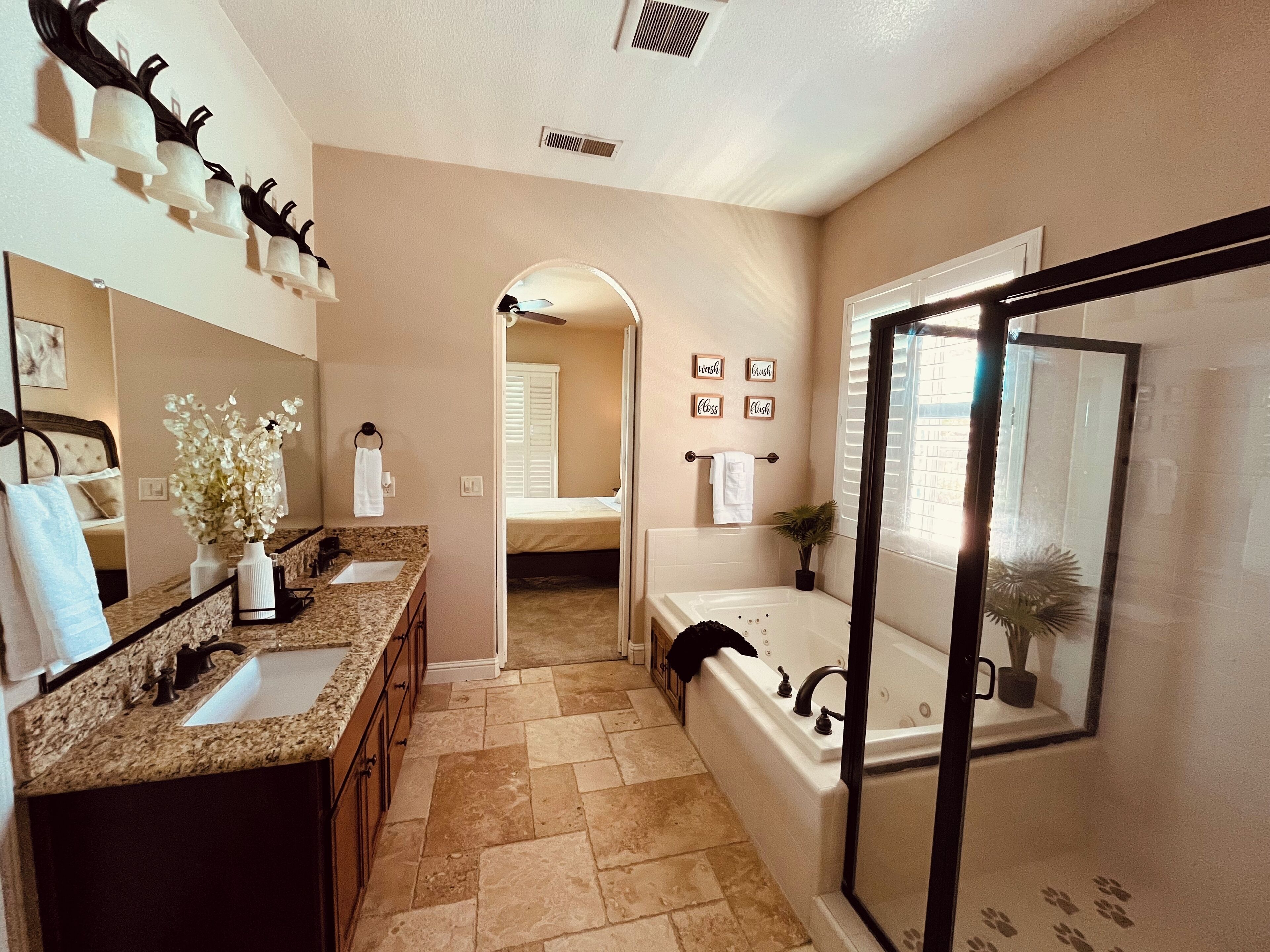 A bathroom with a double sink, a bathtub, a shower area, and a mirror.