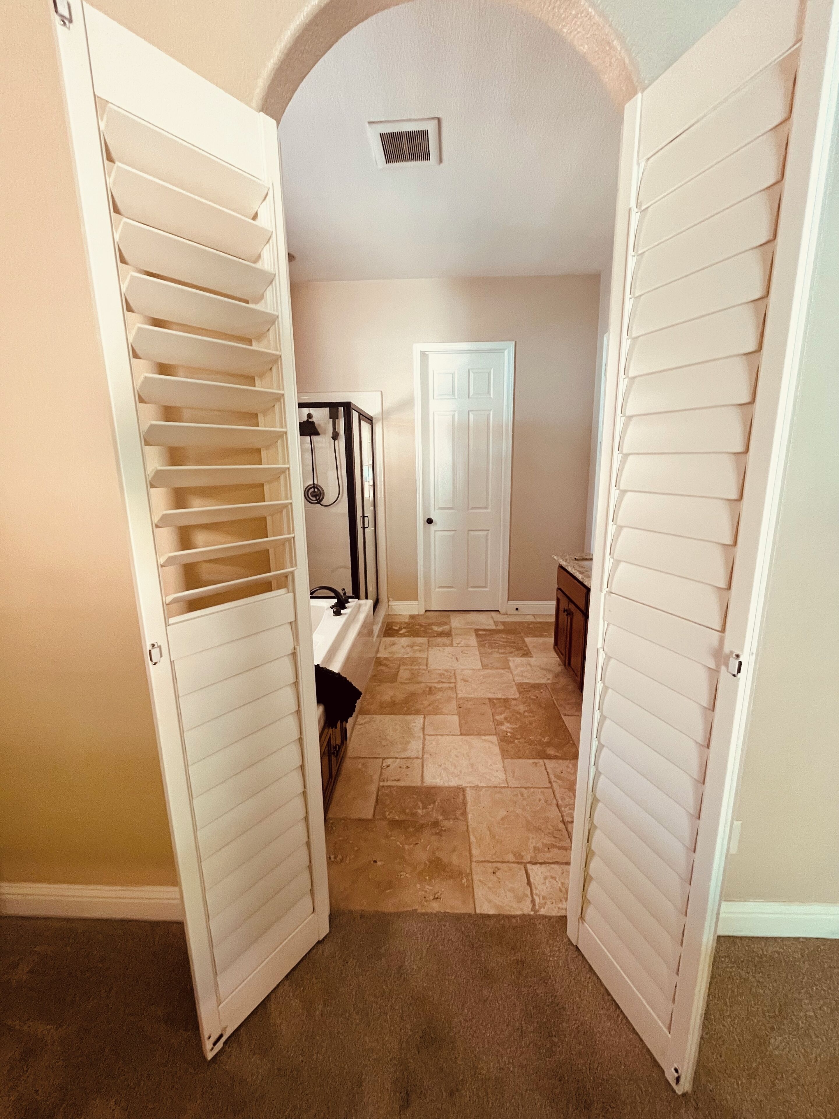 A hallway with a bathtub, a door, and a small bench.
