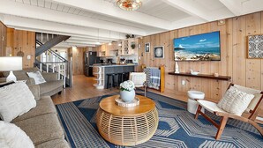 A modern interior with a kitchen, dining area, and living room, featuring wooden walls, a large painting, and a staircase. - Oceanfront Private Home With Amazing Views (Ocean City)