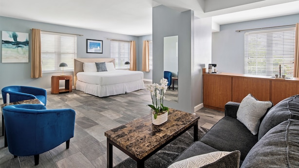 Quarto de hotel moderno com uma cama, um sofá, uma mesa de centro e uma área de trabalho.