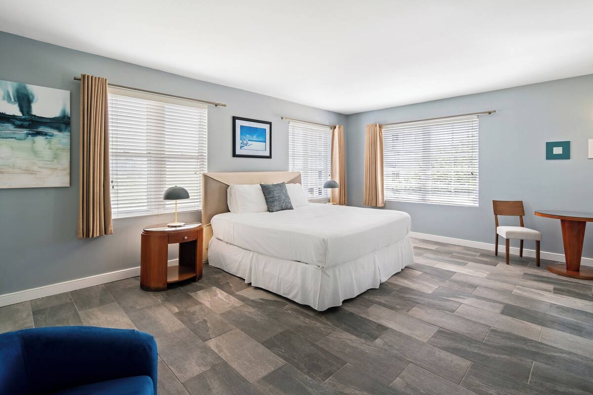 A bedroom with a bed, two bedside tables, a chair, and a desk.