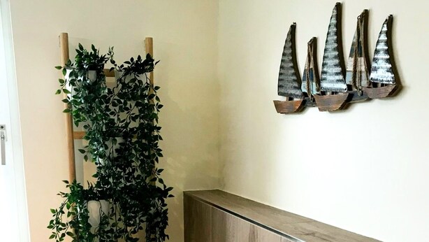 Un banco de madera con una escultura de barcos de vela en la pared.