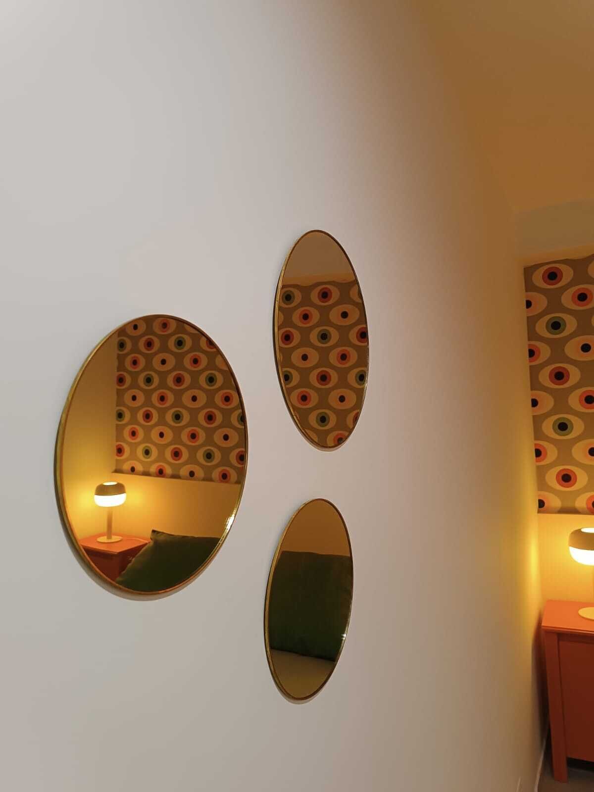 Drei ovale Spiegel an einer Wand mit dekorativer Tapete.