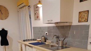 A compact kitchen with a central island, a sink, and a stove. There is a clock on the wall and a mannequin in the corner. - Vacation home in the center 5 minutes from the National Museum, Duomo, Sanita (Napoli)