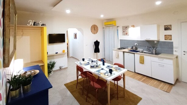 A compact living space with a dining area, a kitchenette, and a TV mounted on the wall. - Vacation home in the center 5 minutes from the National Museum, Duomo, Sanita (Napoli)