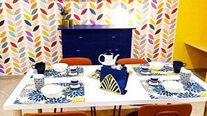 A dining table set with blue and white patterned placemats, two orange chairs, and a blue cabinet in the background. - Vacation home in the center 5 minutes from the National Museum, Duomo, Sanita (Napoli)