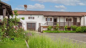 A traditional building with a tiled roof, a wooden balcony, and a garden with various plants and flowers. - Lovely apartment in Divaca with WiFi (Divaca)