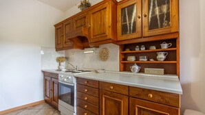 A kitchen with wooden cabinets, a white countertop, a stove, and a sink. - Lovely apartment in Divaca with WiFi (Divaca)