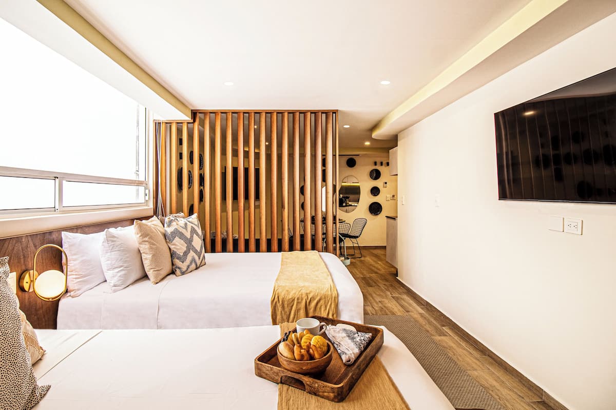 Una habitación de hotel moderna con cama, mesita de noche y una bandeja con pasteles.