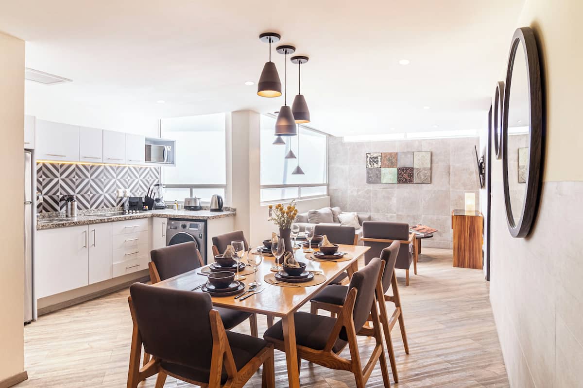 Una cocina moderna con comedor, muebles de madera e iluminación colgante.
