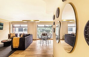 Ein modernes Wohnzimmer mit einer Couch, einem Couchtisch und einem Essbereich mit Stühlen und einem Tisch.