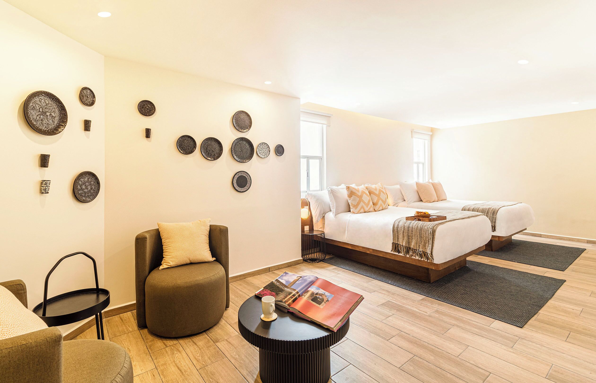 Une chambre d’hôtel moderne, équipée d’un lit, d’un coin salon et de quelques assiettes décoratives accrochées au mur.