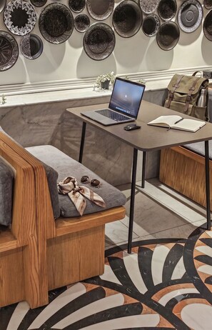 A modern room with a sofa, a table with a laptop, a backpack, and decorative plates on the wall.
