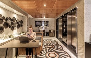 Ein modernes Interieur mit Holzboden, einer Wand mit dekorativen Tellern, einer Sitzecke mit einem Laptop und einem großen Aufzug.