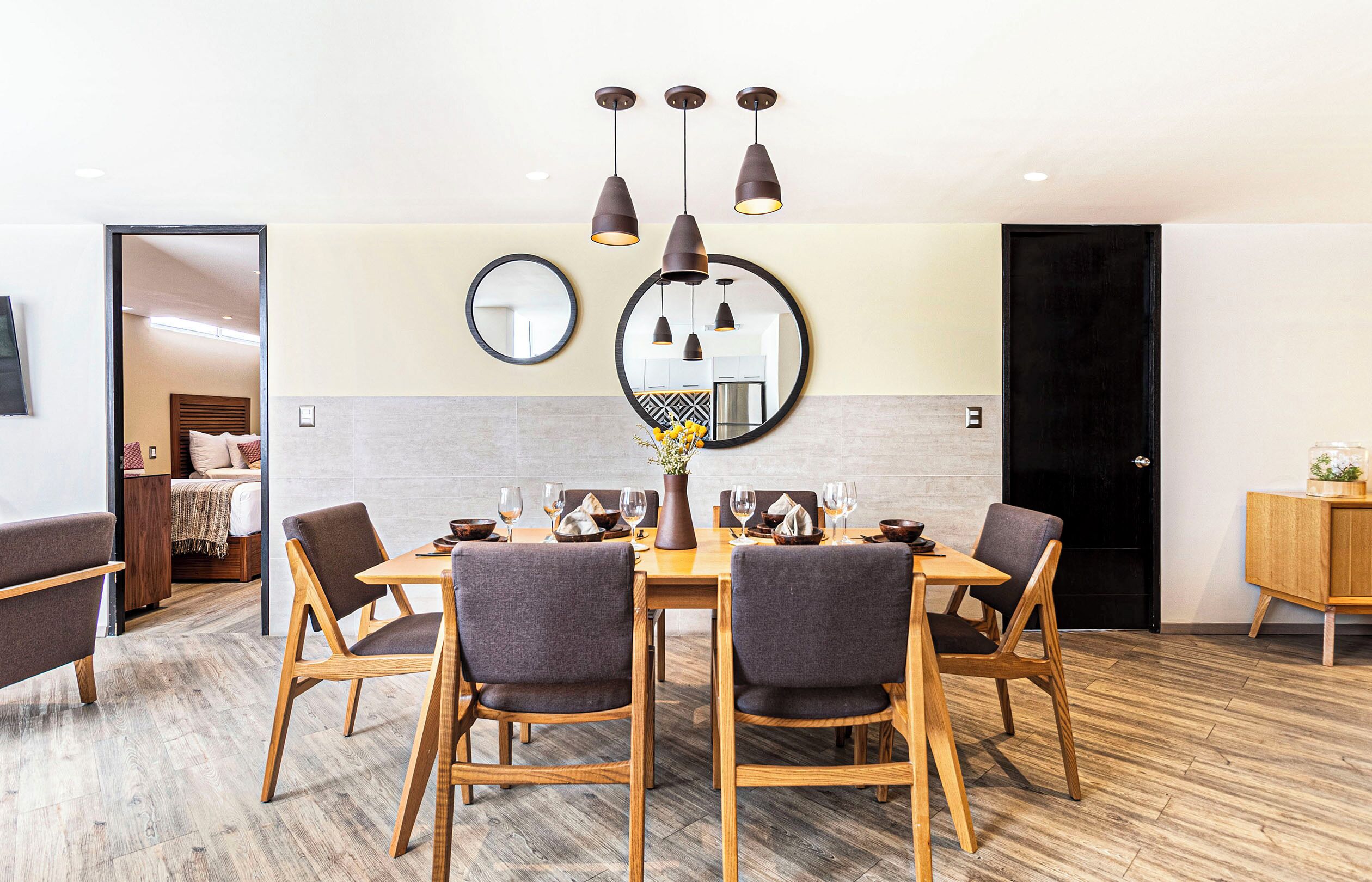 Een eetgedeelte met een ronde tafel, zes stoelen en hanglampen.
