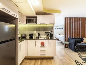A compact kitchen with a microwave, stove, and modern appliances. - Kukun Grand Chapultepec (Mexico City)