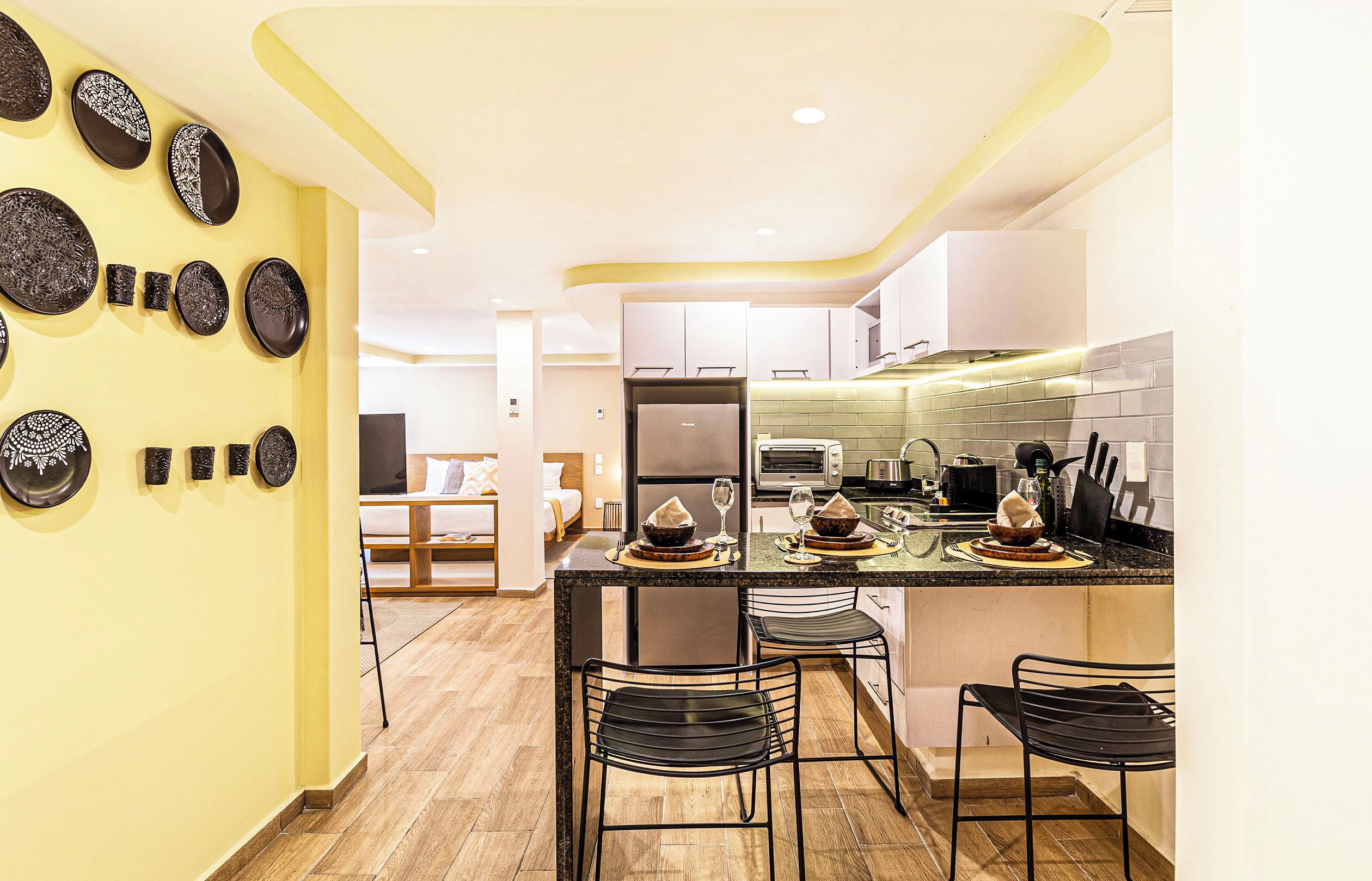 Cocina moderna con una isla central, taburetes de bar y un área de comedor con sofá y mesa.