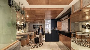 A modern hotel lobby with wooden ceiling, seating areas, a reception desk, and a patterned floor. - Kukun Grand Chapultepec (Mexico City)